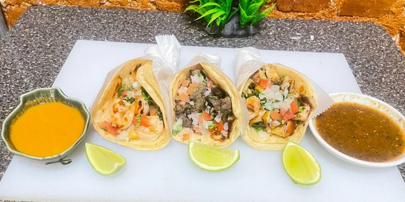 Three street-style tacos with shrimp, steak, and chicken served with fresh salsas